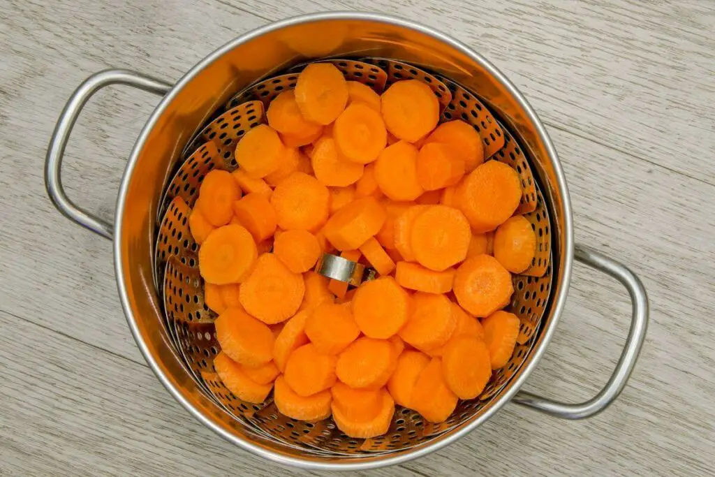 Carrots in a strainer on a wooden table, perfect for those with IBS who prefer vegetables.