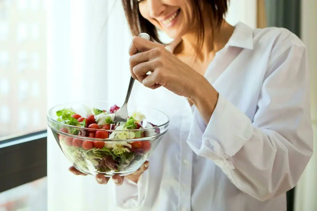 A woman holding a bowl of salad while taking ibs medication.