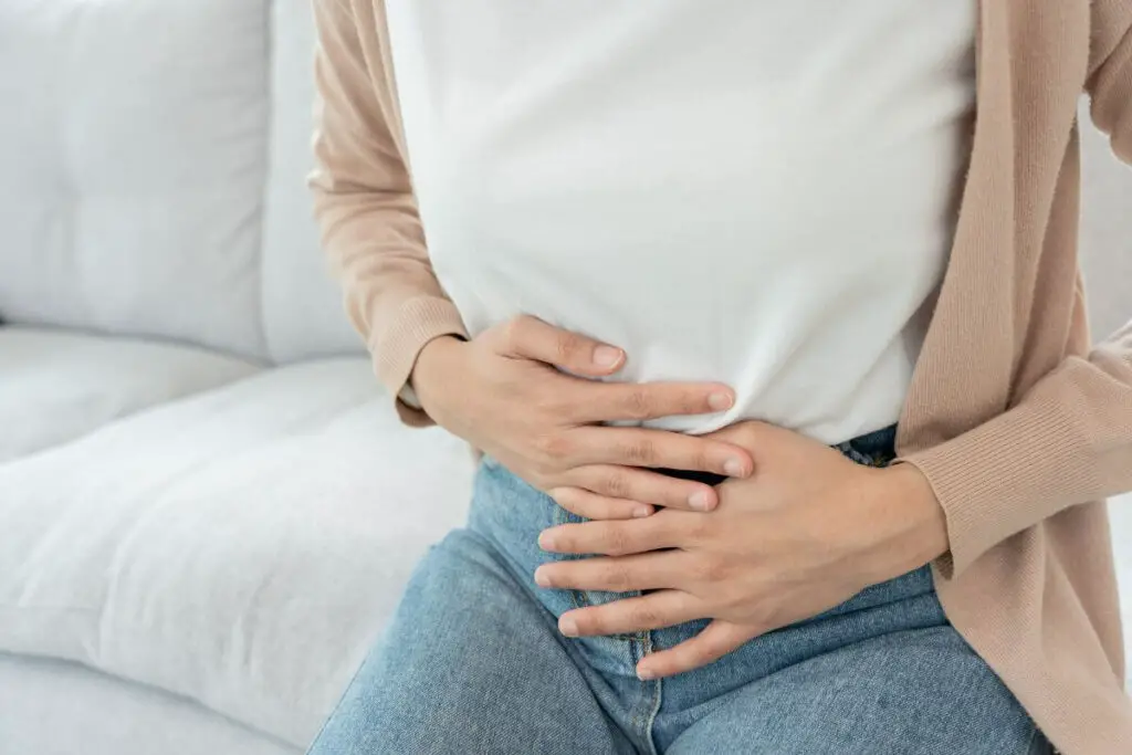 A person holding her stomach due to IBS pain.