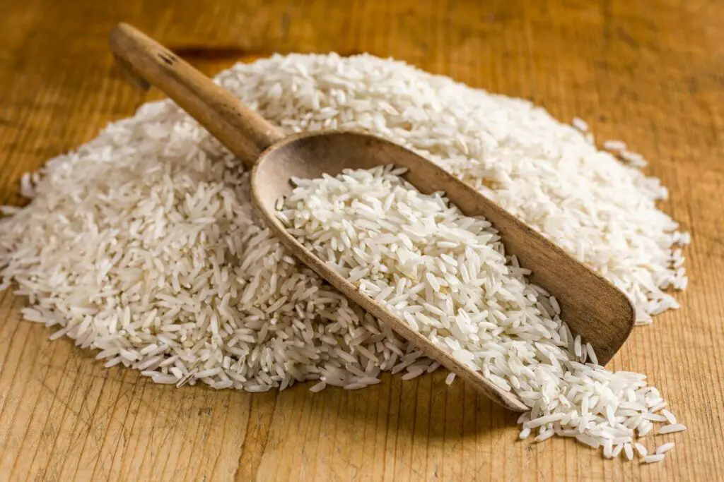 A pile of white rice, a high fodmap grain, on a wooden table.