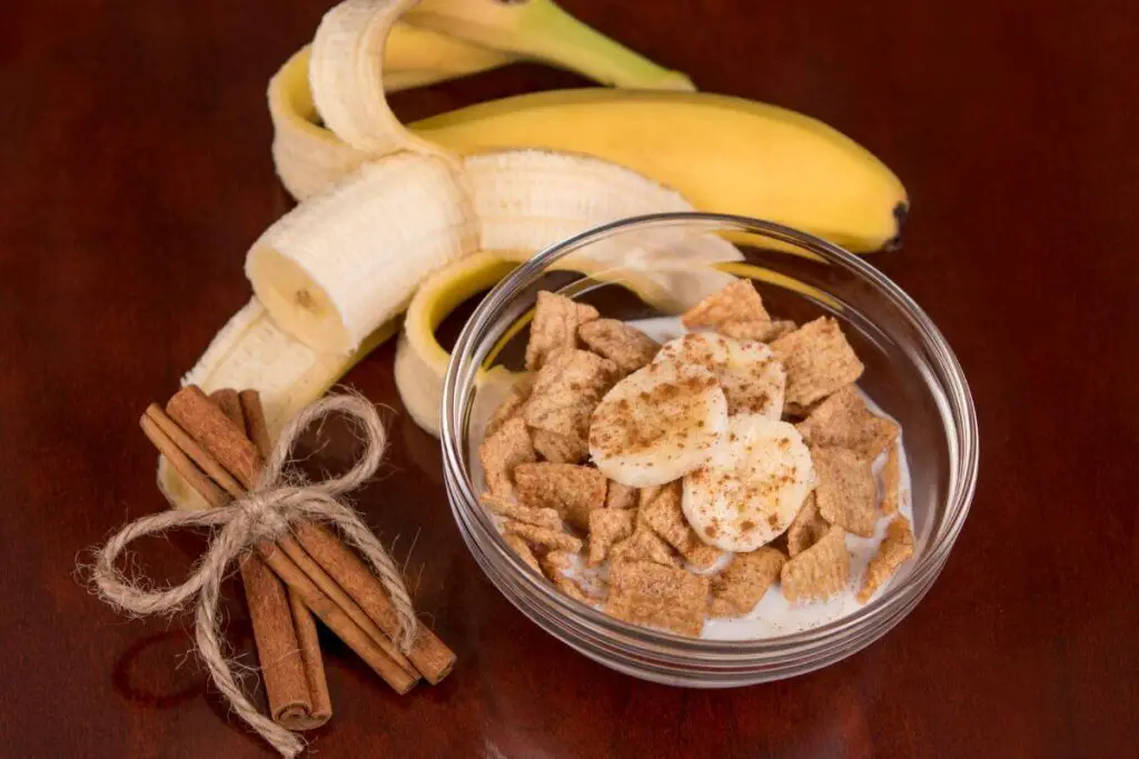 A bowl of cereal with cinnamon and bananas, perfect for those searching for the best snacks for IBS, displayed on a rustic wooden table.