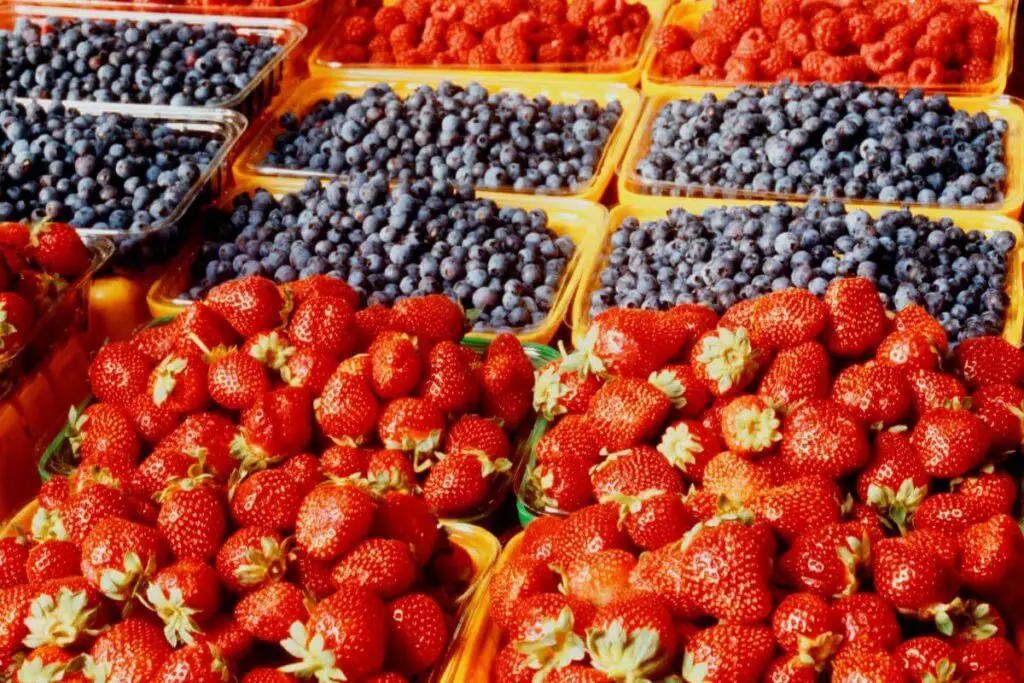 A variety of vibrant berries, including strawberries, blueberries, and raspberries, are on display at a market.