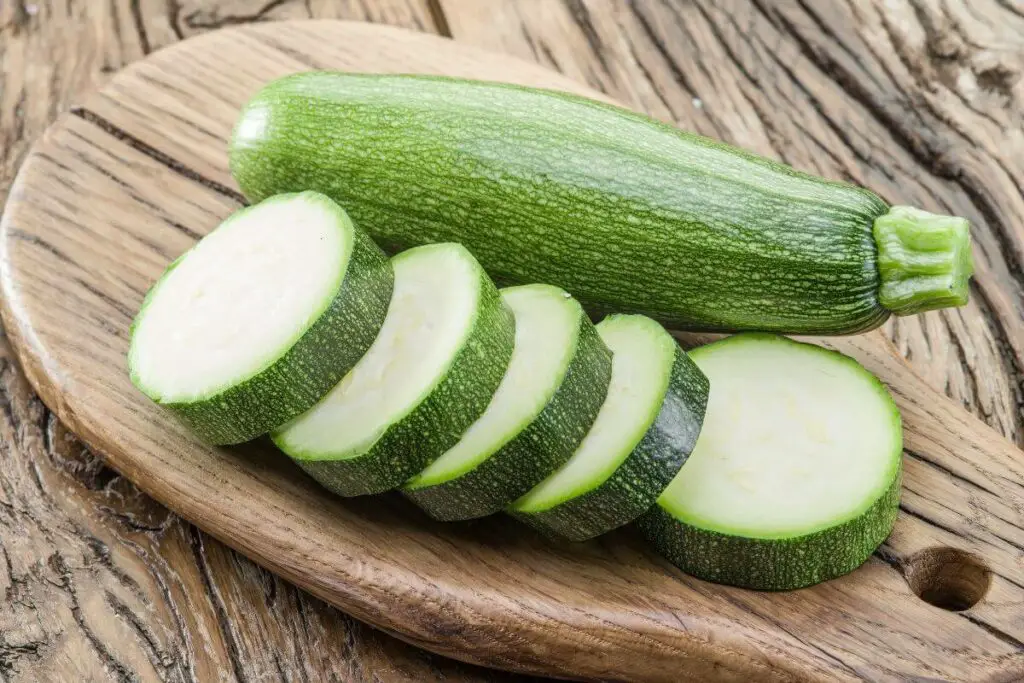 Zucchini slices on a wooden cutting board, suitable for individuals with IBS.