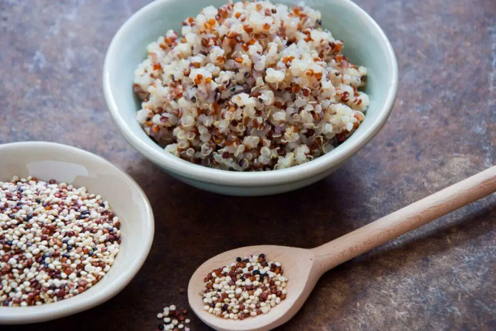 Two bowls of quinoa and a wooden spoon, the perfect snacks for IBS.