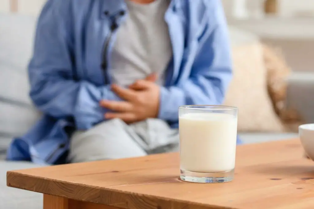 A man sitting on a couch with a glass of dairy milk.