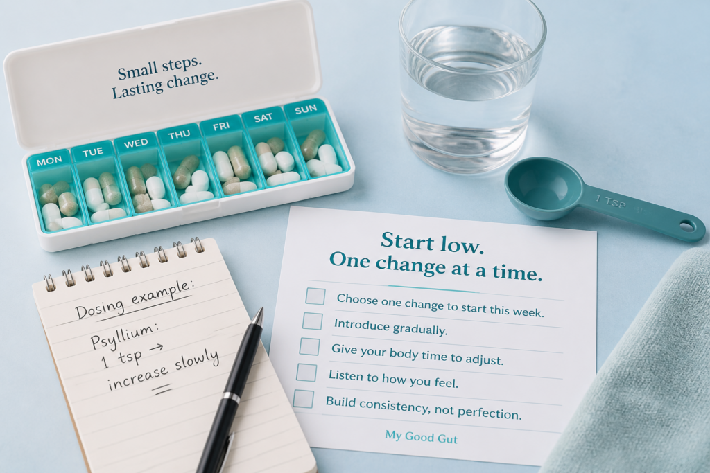 A pill organizer with capsules, Over-The-Counter Medications for IBS, a glass of water, a blue measuring spoon, a notepad with a psyllium dosage note, and a gradual changes checklist are arranged on a light blue surface.