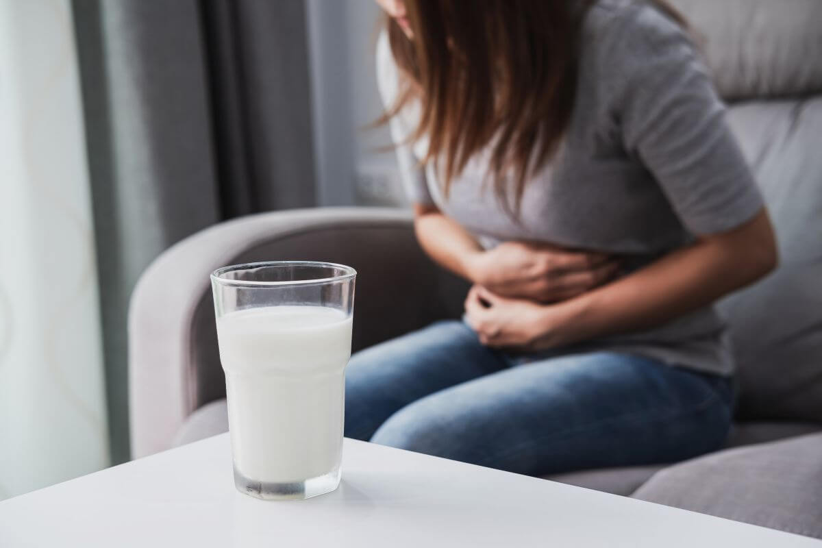 A woman sitting on a couch with a glass of milk, enjoying her dairy beverage.