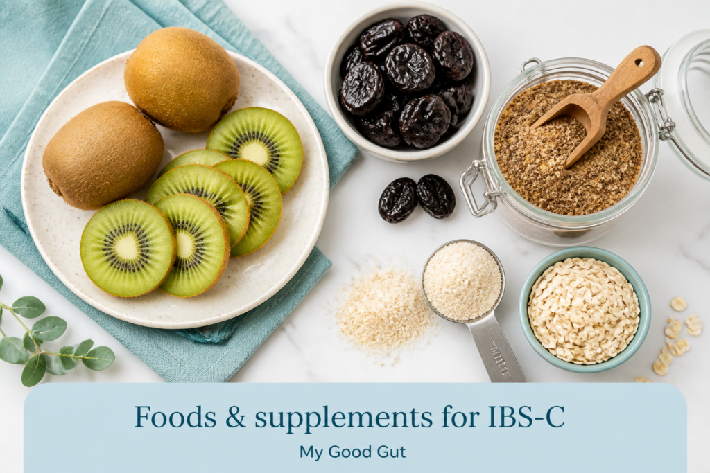 A plate of whole and sliced kiwis, dried prunes, flaxseed, oat flakes, and psyllium husk on marble with the text “Foods & supplements for IBS-C”—a perfect visual guide for your IBS constipation diet.