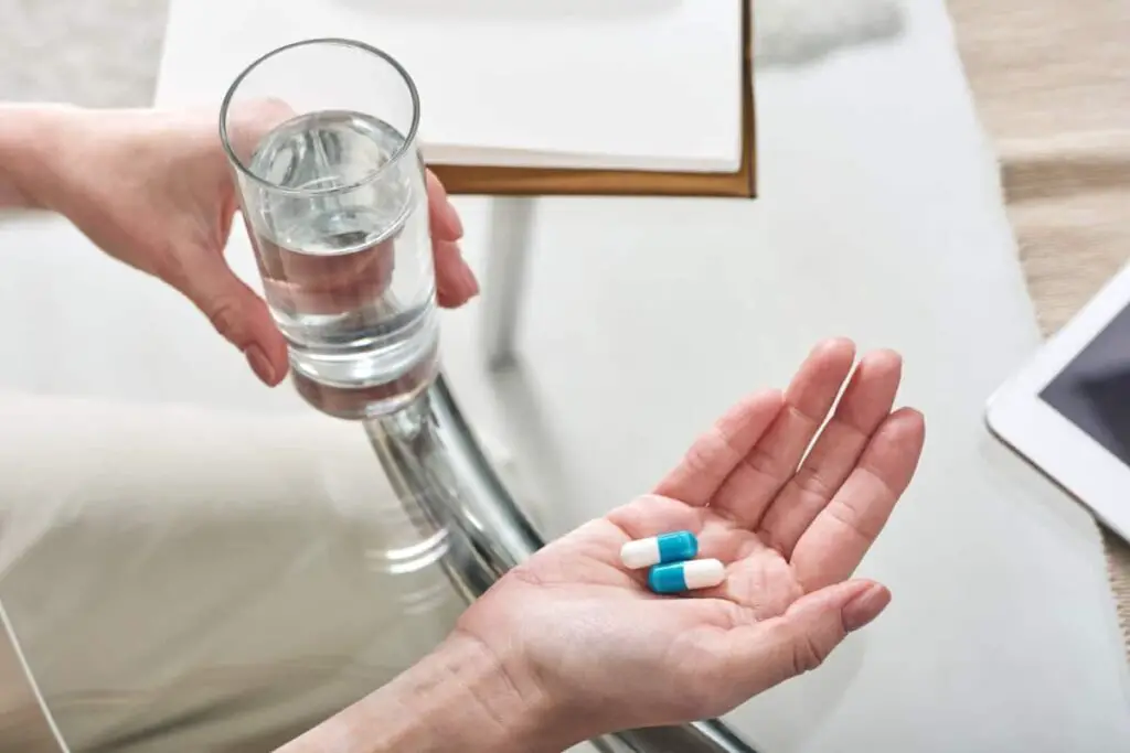 A woman holding medication and water.