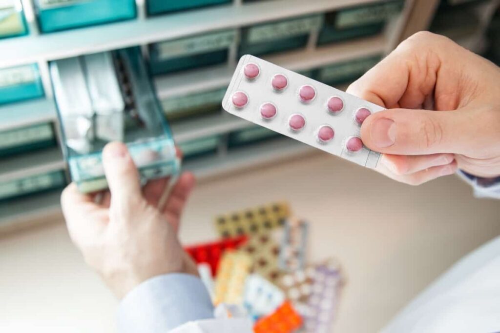 A pharmacist is holding a pack of pills.