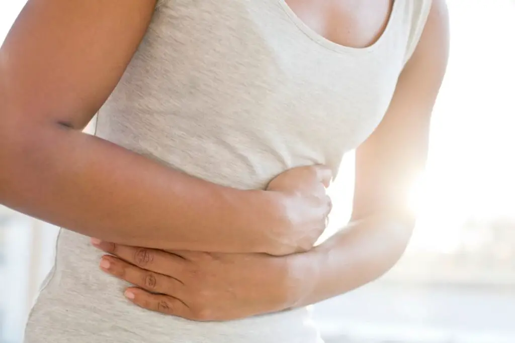 A woman is holding her stomach due to digestive discomfort caused by IBS-C.
