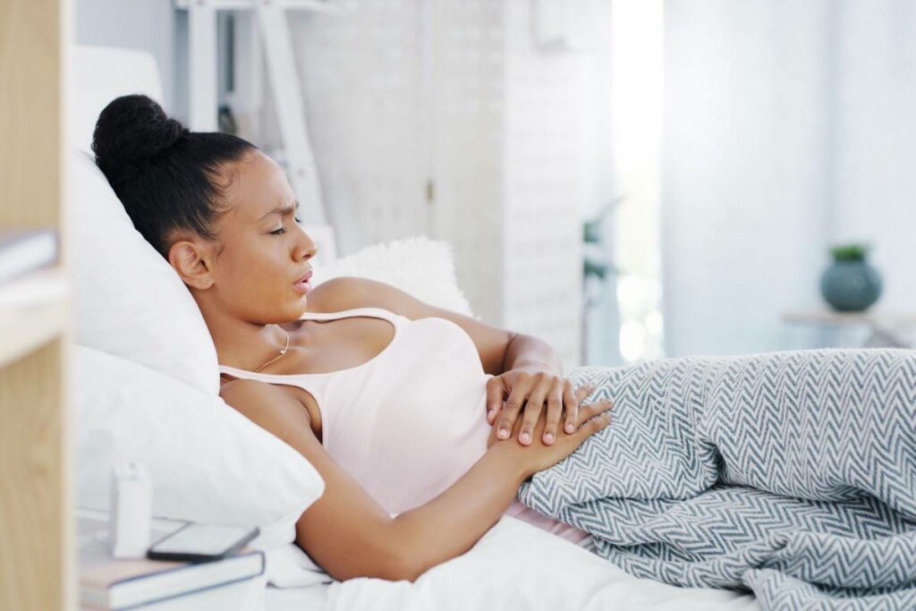 A woman experiencing IBS-D symptoms while lying in bed.