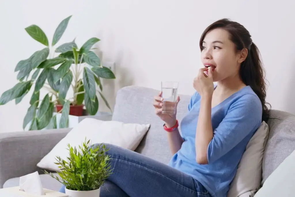 A woman consuming ibs medication and hydrating with water.